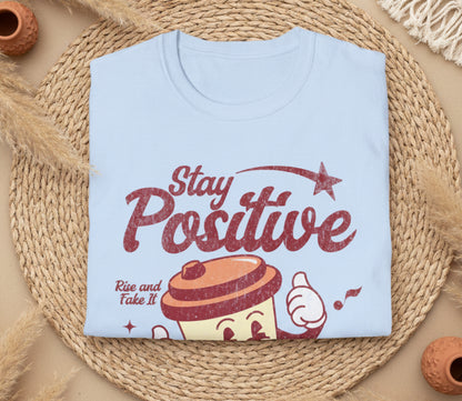 Light blue t-shirt with 'Stay Positive' text and cupcake graphic on a white background