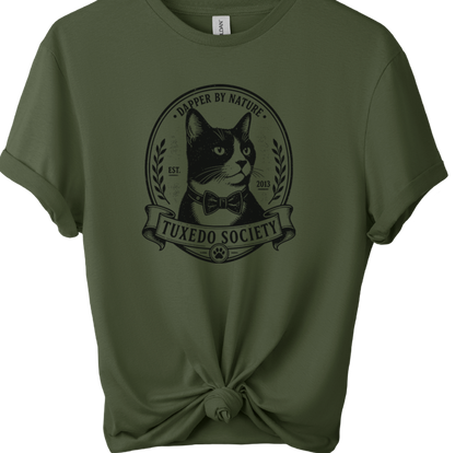 An military green short-sleeve t-shirt on a wooden hanger, styled with a knot at the bottom hem. The shirt features a black graphic print of a cat wearing a bow tie inside an oval frame with the text 'TUXEDO SOCIETY' and dapper BY NATURE'.