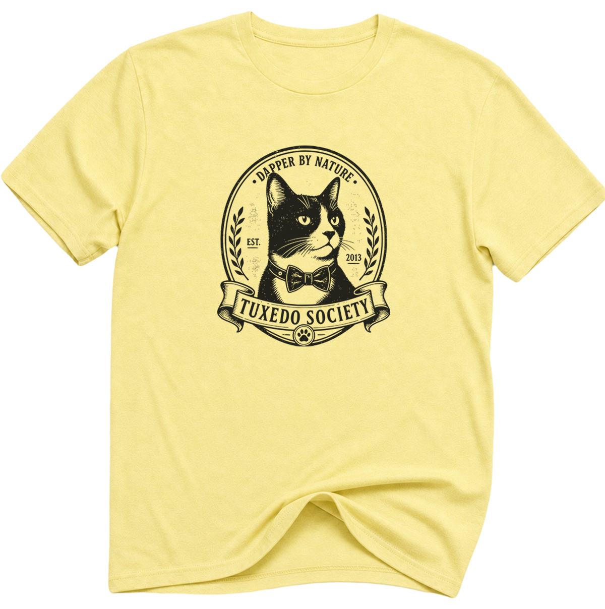 A cornsilk  folded-sleeve crewneck t-shirt featuring a black graphic print of a cat wearing a bow tie inside an oval emblem with the text 'TUXEDO SOCIETY' and 'CAPER BY NATURE'.