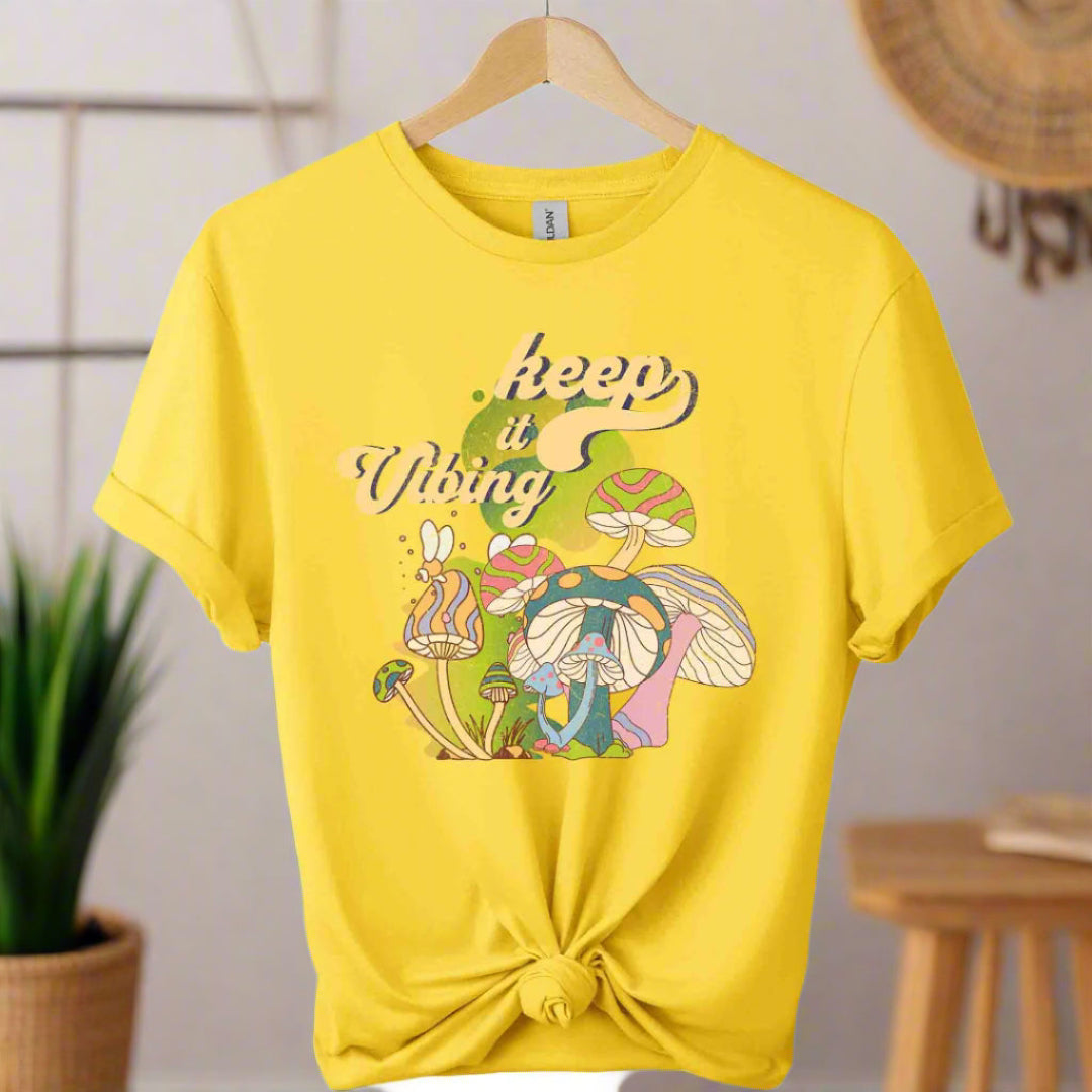 T-shirt color daisy ,unisex with front design mushroom graphics and keep vibing typography ,retro tees 