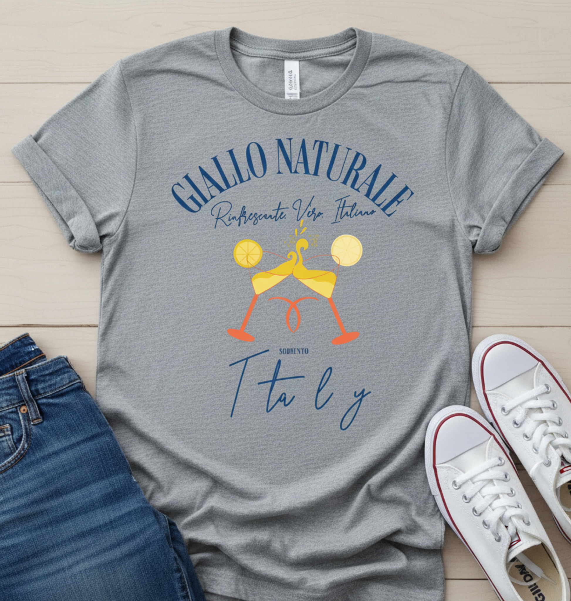 Gray t-shirt with 'Giallo Naturale' graphic design on a wooden surface with jeans and shoes.