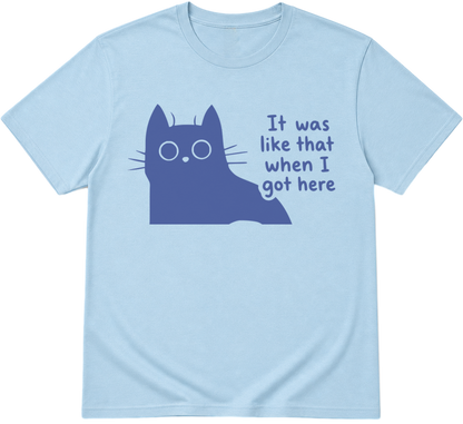 A light blue crewneck t-shirt featuring a dark blue graphic of a cat peeking out from behind with the text 'It was like that when I got here' printed next to it.