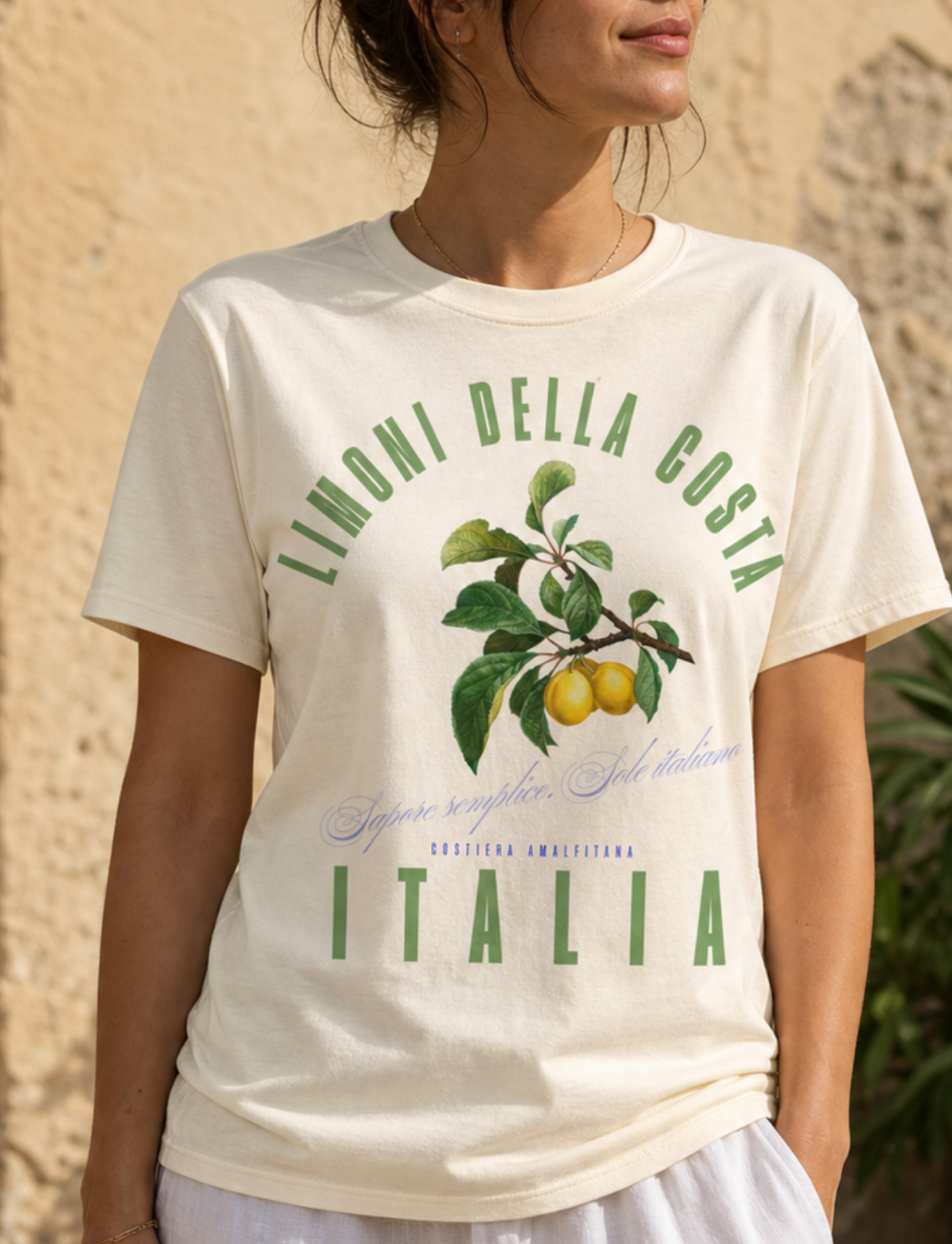 Woman wearing a t-shirt with 'Limonni della Costa Italia' design outdoors.