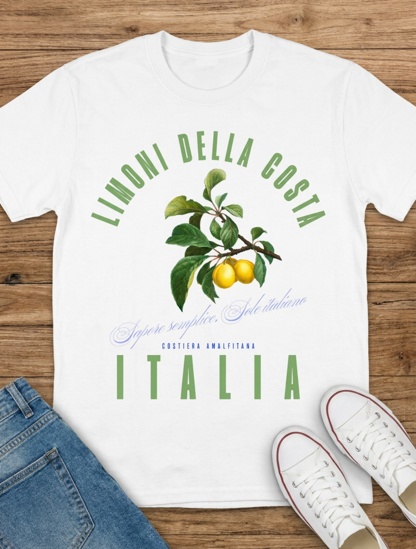 White t-shirt with 'Limonelli della costa Italia' design on a wooden surface with jeans and shoes.
