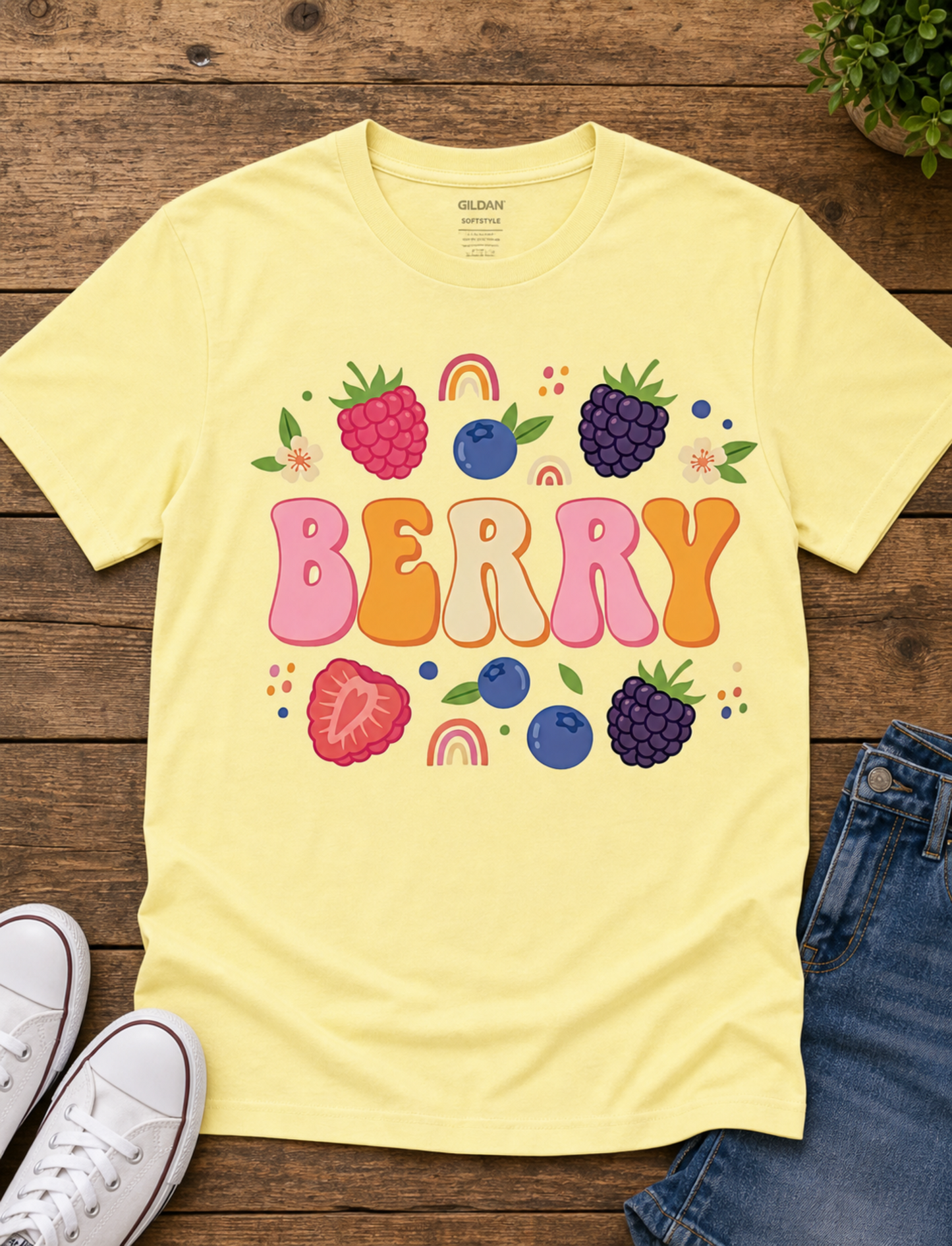 Yellow t-shirt with colorful 'BERRY' design on a wooden surface with shoes and jeans.