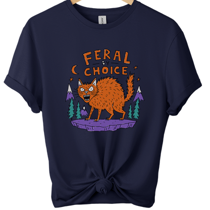 A navy blue softstyle ringspun t-shirt on a wooden hanger, styled with a knot at the bottom hem. The shirt features a graphic of an orange werewolf on a purple rock with pine trees and the text 'FERAL CHOICE'.neilikha
