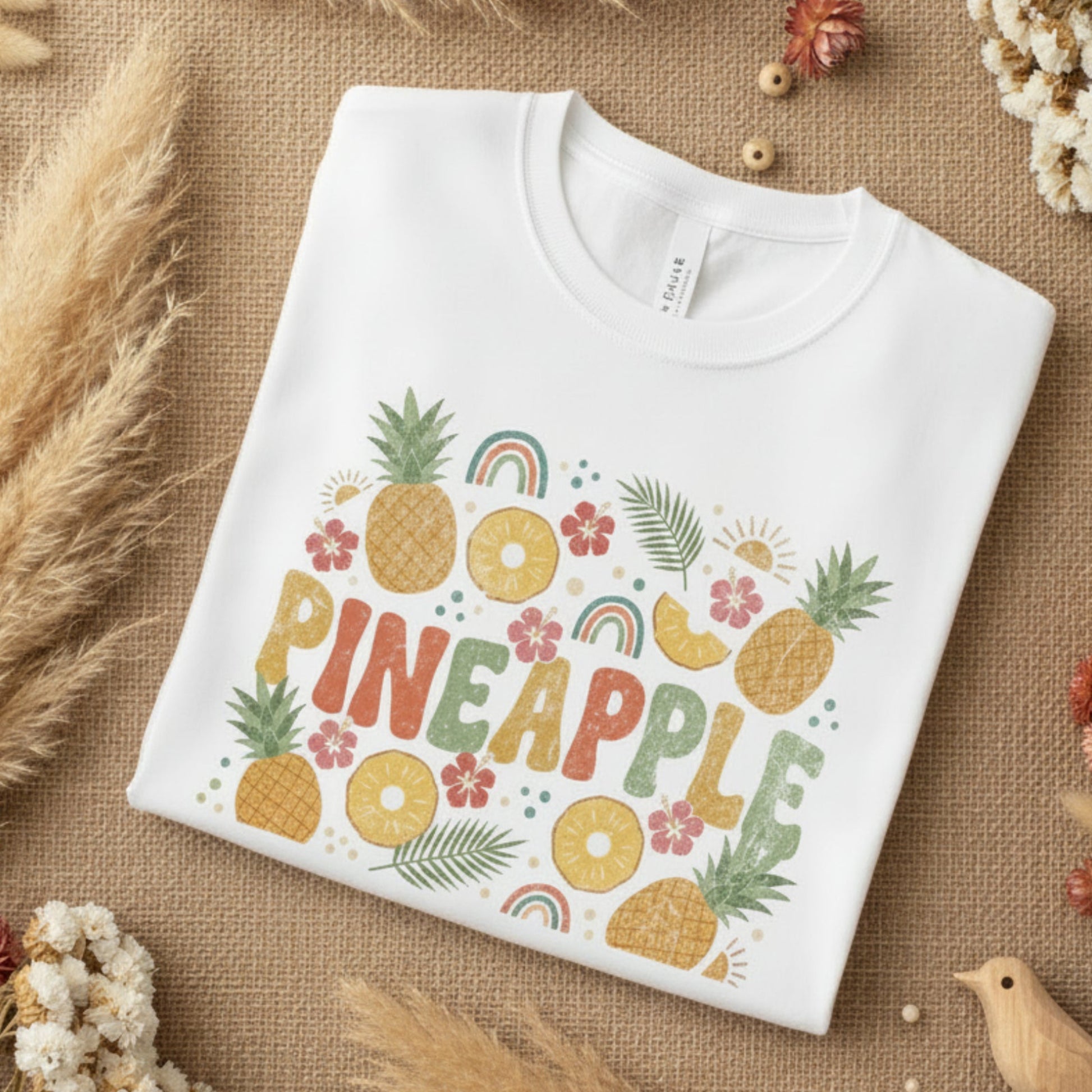 folded White t-shirt with colorful pineapple design on a white background