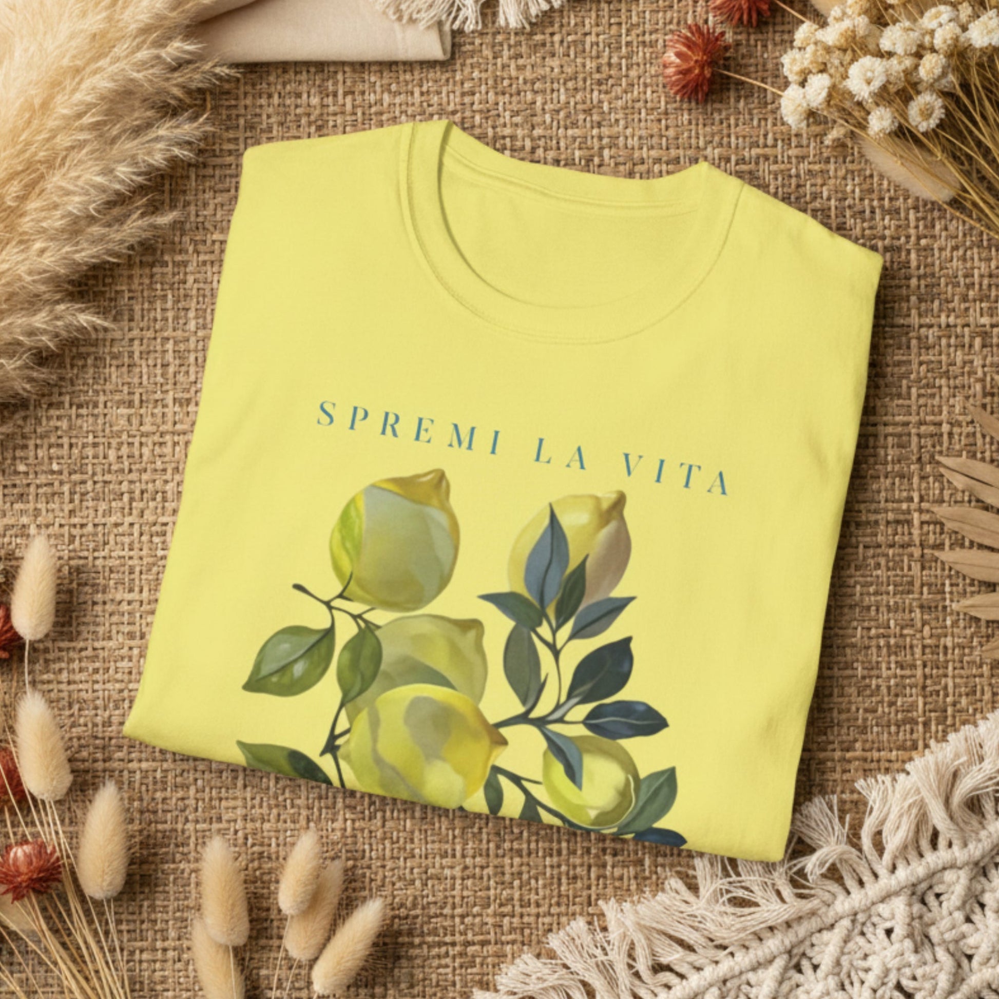 folded corn silk t-shirt with a watercolor Mediterranean lemon graphic and teal Italian text reading Spremi La Vita Italy