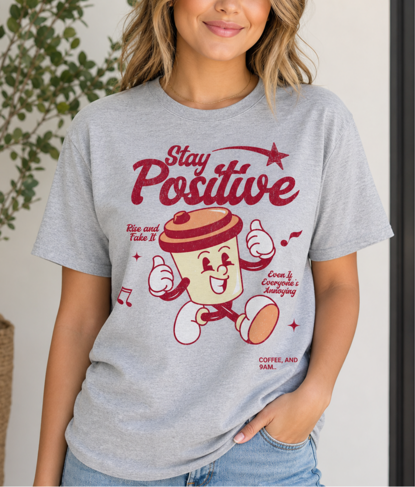 Woman wearing a sport grey t-shirt with a cartoon character and 'Stay Positive' text.