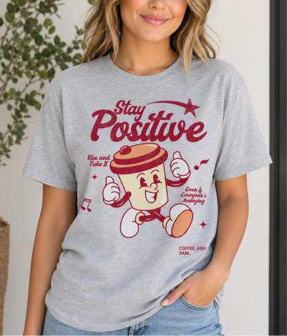 Woman wearing a sport grey t-shirt with a cartoon character and 'Stay Positive' text.