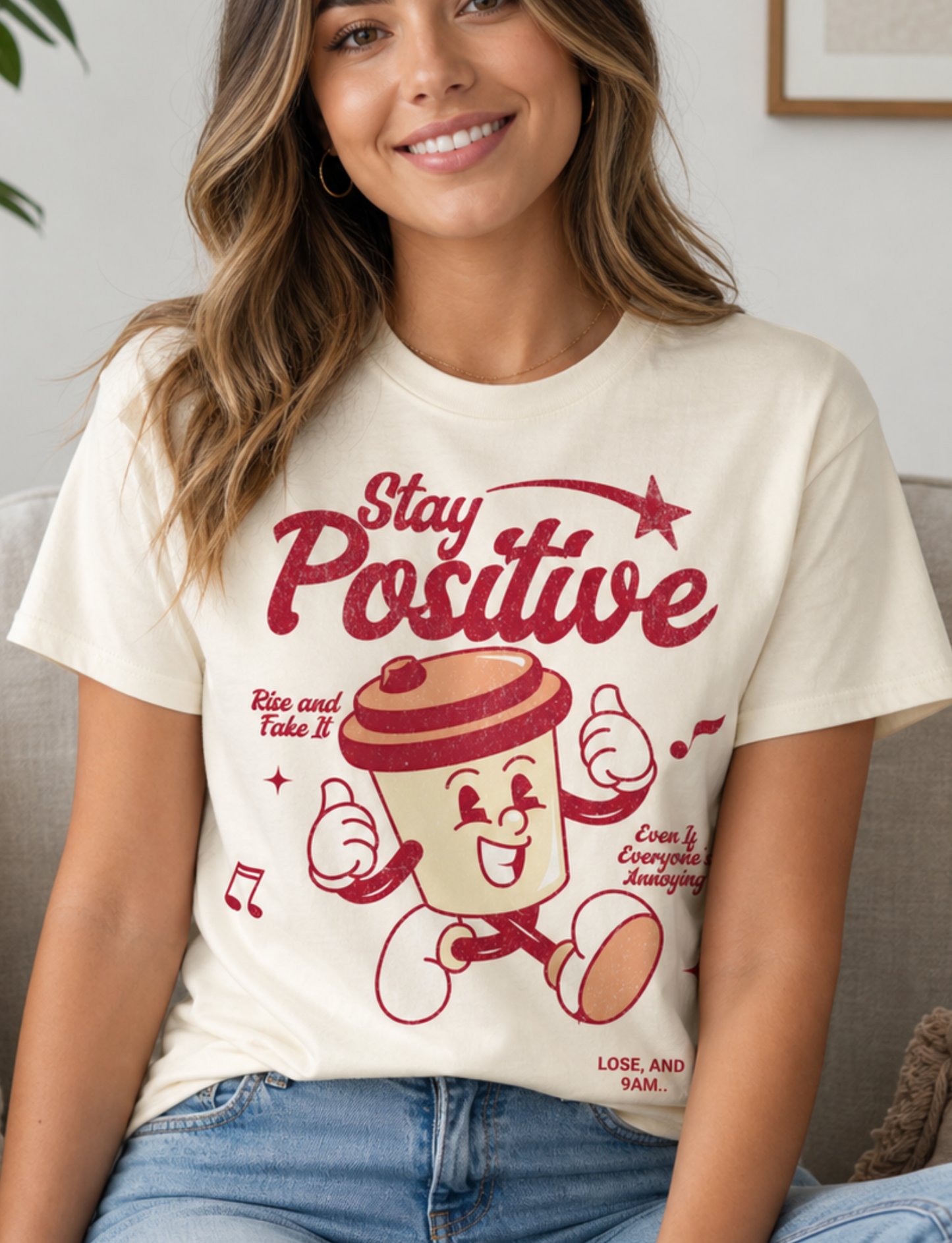 Woman wearing a 'Stay Positive' t-shirt with a cartoon character in a living room.